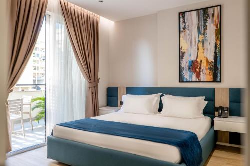 a bedroom with a blue and white bed and a window at Hotel Vino in Durrës