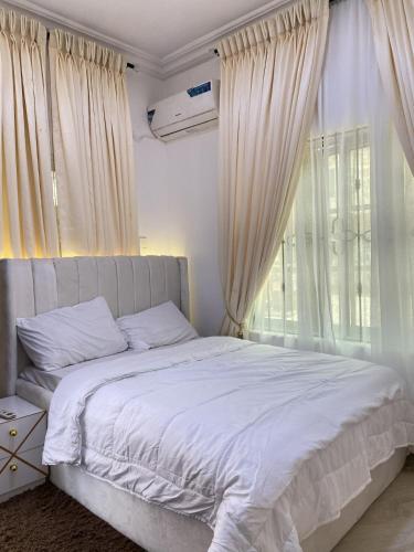 a bedroom with a bed with white sheets and a window at Living Space Home in Lekki