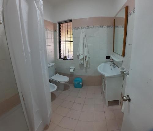 a white bathroom with a toilet and a sink at Palm Beach Resort in Boca Chica