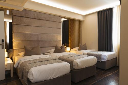 a hotel room with three beds and a wall at Hotel Villa Pace in Međugorje
