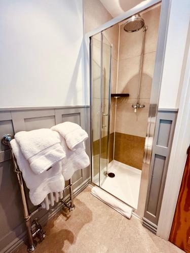 a bathroom with a walk in shower and towels at Carlton Guest Suites - Weymouth in Weymouth