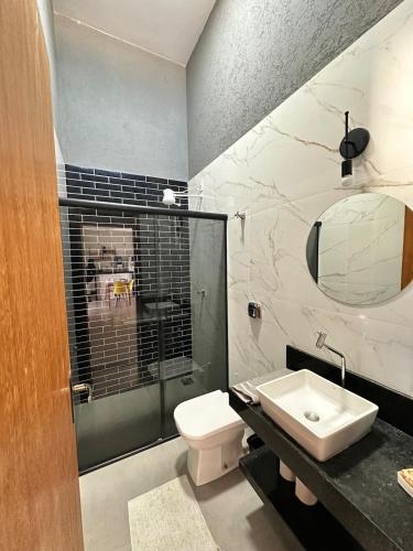 a bathroom with a toilet and a sink and a mirror at Casa 2min do Centro & Piscina in Bonito