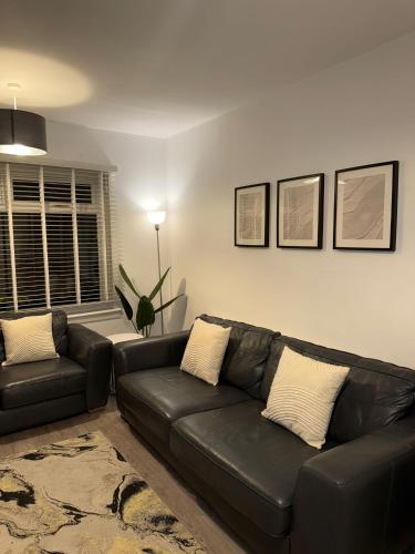 a living room with a black leather couch at Beautifully Designed Pollok House in Glasgow