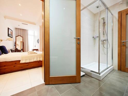 a bathroom with a glass shower and a bed at Good Times in Sliema