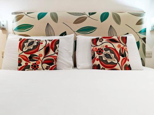 a bed with three pillows and a wall with flowers at Good Times in Sliema