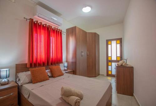 a bedroom with a large bed with red curtains at The Terrace in Xgħajra