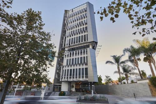 a tall white building with trees in front of it at WorldHotels Acueducto Guadalajara in Guadalajara