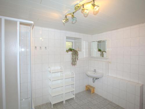 a white tiled bathroom with a sink and a shower at Villa Lisa in Glowe
