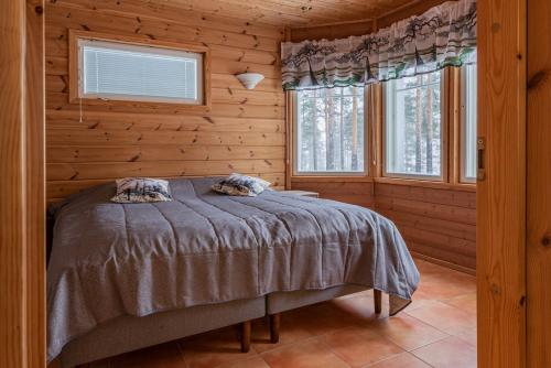 a bed in a wooden room with two windows at Pielusrinne in Hattusaari