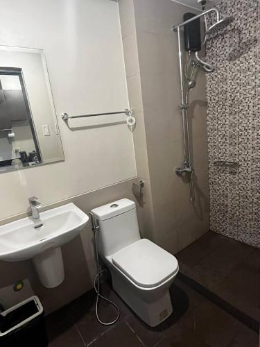 a bathroom with a white toilet and a sink at Aurora Escalades Residences in Manila