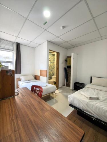 a room with two beds and a wooden table at Tang Hotel in Alor Setar