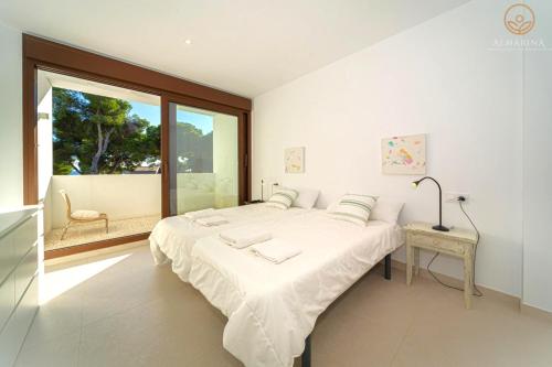 a white bedroom with a large bed and a window at MARETA - Managed by Almarina in Teulada