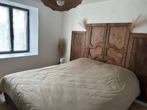 a bedroom with a bed with a wooden headboard and a window at Les Granges Dorées in Châtillon