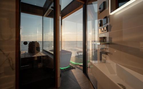 a bathroom with a view of the ocean through glass at Luxury Resort Reiu in Reiu