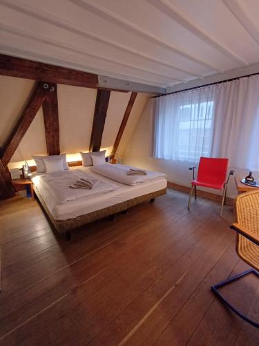 a bedroom with a bed and a red chair at Schiefes Haus in Ulm