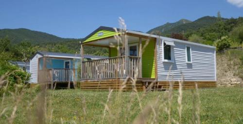 a tiny house with a porch on a field at ZEcamping 4 étoiles animaux acceptés animations piscine chauffée in Rosans