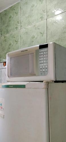 a microwave sitting on top of a refrigerator at Pequena e graciosa in Estação Senador Camará