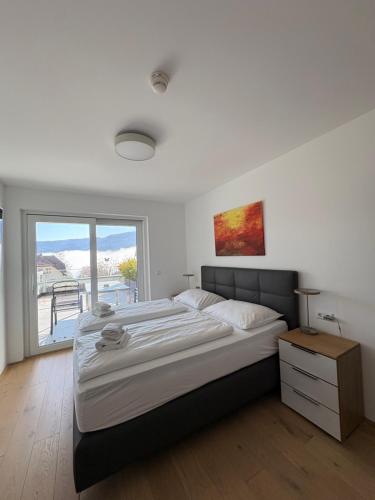 a bedroom with a large bed and a large window at Sun Terrace Apartment 04 I Gerlitzen-Ossiachersee I Alpe Maritima in Annenheim