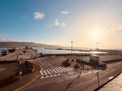a view of a street with a river and the sun at Pier House Luxury Apartment in Dingle
