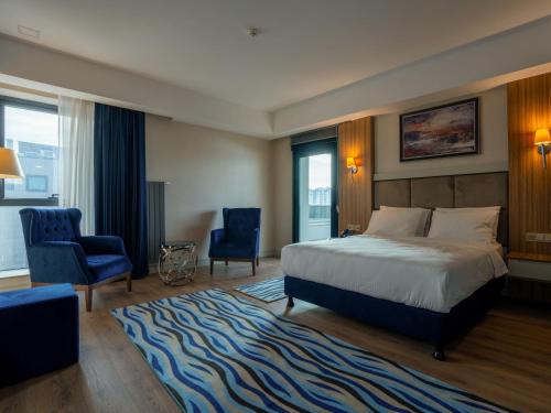a bedroom with a bed and two blue chairs at Elite World Comfy Diyarbakır in Diyarbakır