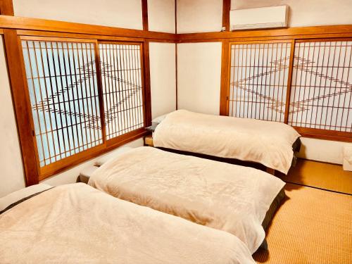 two beds in a room with two windows at 波止場の海まで徒歩30秒の貸切宿 "ギョグンミニ" "Gyogun Mini" in Ainan