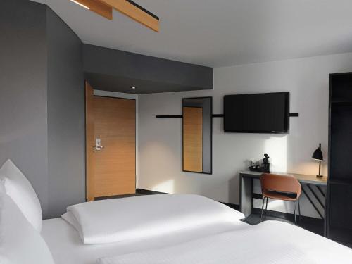 a bedroom with a bed and a tv on the wall at B&B Hotel Krefeld-City in Krefeld