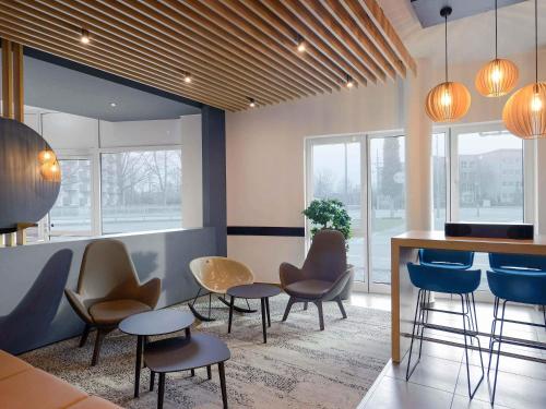 a bar with chairs and tables in a room with windows at B&B Hotel Krefeld-City in Krefeld
