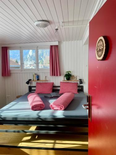 a bedroom with a large bed with red pillows at Balmers Hostel in Interlaken