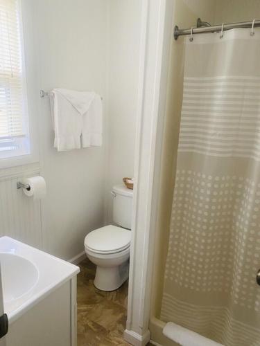 a white bathroom with a toilet and a shower at Snug Harbor Marina and Resort in Chincoteague
