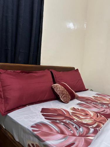 łóżko z dwiema czerwonymi poduszkami na górze w obiekcie Home services w mieście Dakar