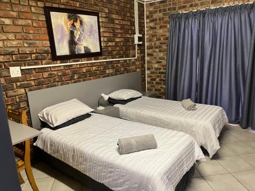 a room with two beds and a brick wall at 5 Moepel in Potchefstroom