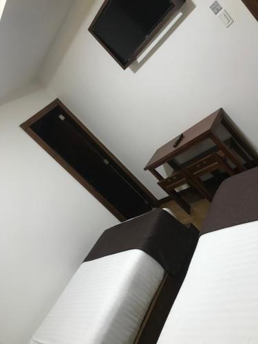 una camera da letto con un letto, una scrivania e una TV di HOSTAL CAMIL a Loja
