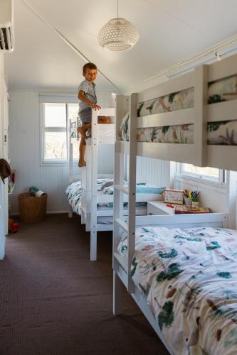 a boy is standing on the top of a bunk bed at Croftby Hills - Scenic Rim in Croftby