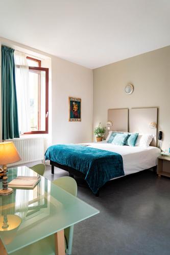 a bedroom with a large bed and a table at Hôtel du Musée de l'Eau in Pont-en-Royans