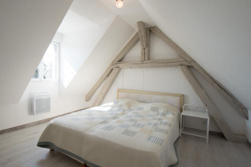 a white bedroom with a bed in a attic at La maison bleue in Lusigny-sur-Barse