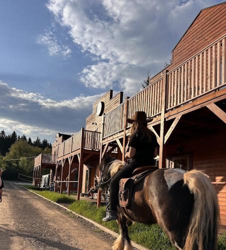 a woman riding a horse down a street at Góry Stołowe Camp - Rodzinne pole biwakowe, Kampery, Przyczepy, Namioty in Radków