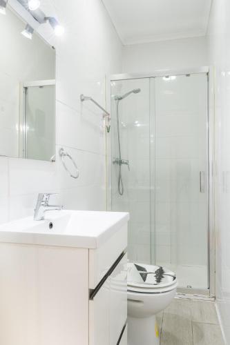 a white bathroom with a shower and a toilet at Suites - Elevador da Bica in Lisbon