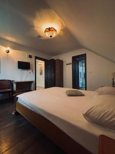 a bedroom with a large bed and a room with a desk at Vila Antanta Podu' Cu Lanturi in Bacău
