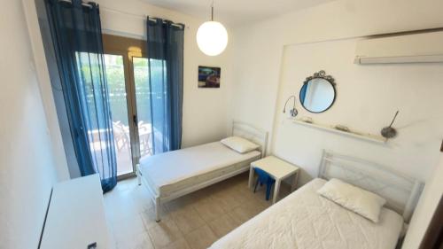 a small bedroom with two beds and a mirror at Oikos Apartment in Hanioti