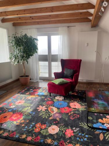 a living room with a red chair and a flower rug at Fewo extraschön - Dachgeschoss in Lindau