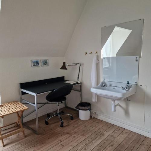 a bathroom with a sink and a desk and a mirror at Patriciavilla tæt på centrum in Haderslev