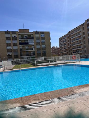 a large blue swimming pool in front of buildings at Apartamentos Bajo La Viga con Piscina in Salamanca