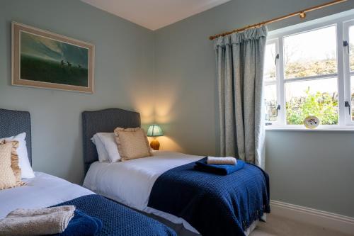 a bedroom with two beds and a window at Skinnel Cottage in Kirkcudbright