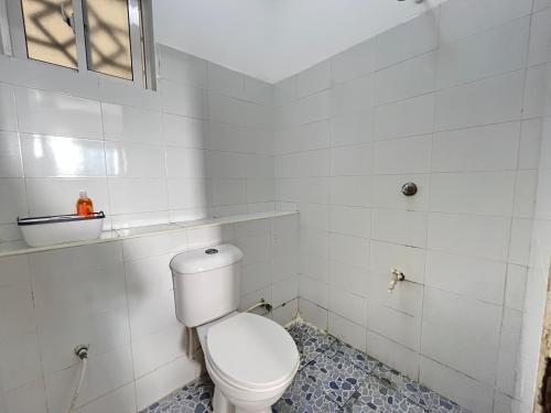 a white bathroom with a toilet and a window at Azure Stays in Mombasa