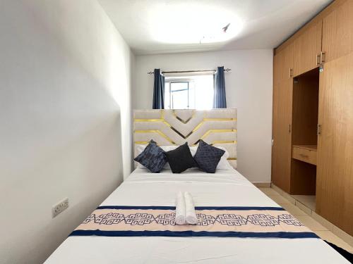 a bedroom with a white bed with black pillows at Azure Stays in Mombasa