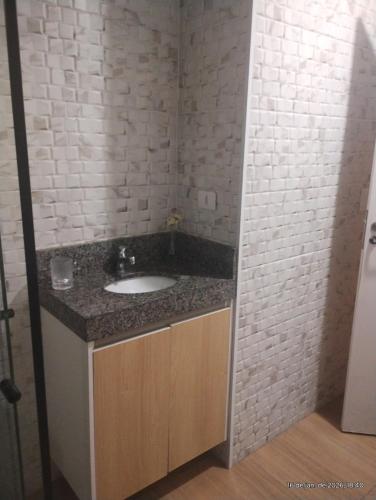 a bathroom with a sink and a brick wall at Casa Magalhães Hospedaria in Extrema