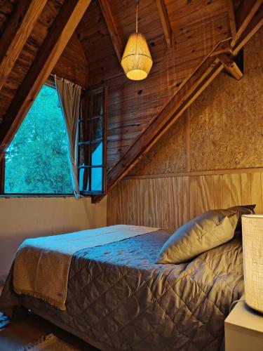 a bedroom with a bed in a room with a window at Bosque Hostel in Villa Traful