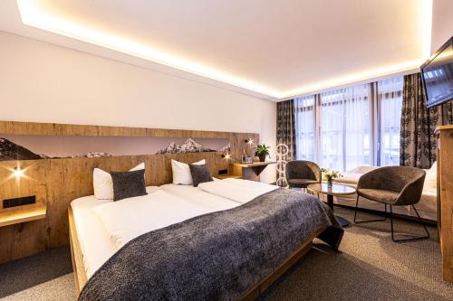 a hotel room with a large bed and a tv at Hotel AlpinaRos in Berchtesgaden