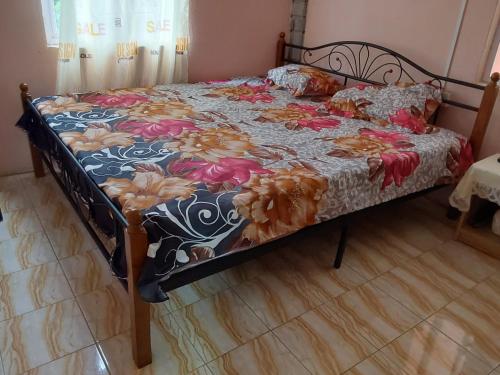 a bed with a floral comforter on it in a bedroom at mango guest house in La Ferme