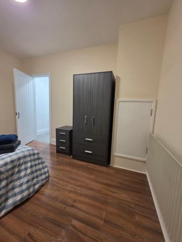 a bedroom with a black cabinet and a wooden floor at ELI STAY Ensuite rooms in Ipswich